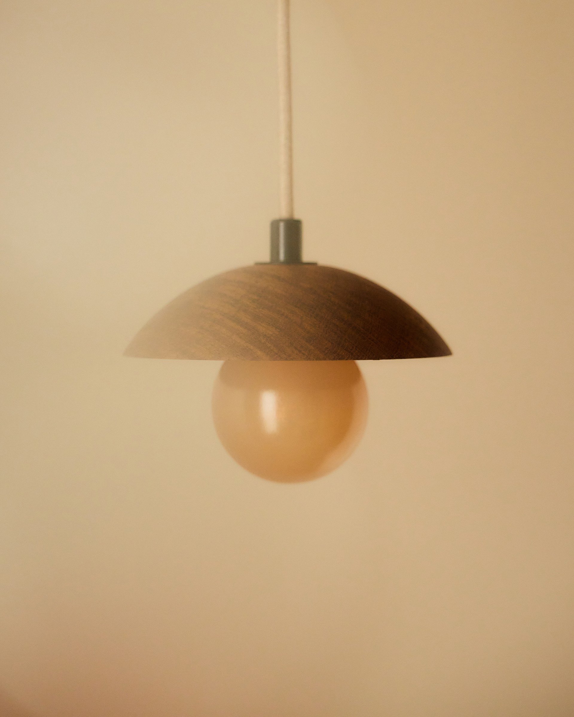 Sculptural pendant light against a softly textured wall